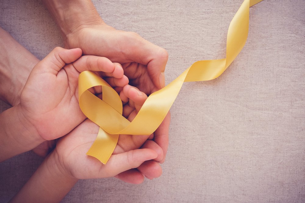 Adult,And,Child,Hands,Holding,Yellow,Gold,Ribbon,,Sarcoma,Awareness,